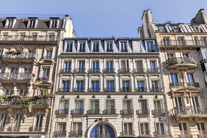 A multi-story building with a classical architectural style, featuring ornate balconies and a central entrance with a decorative arch.
