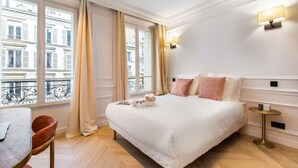 A hotel room with a large bed, a small table, and a chair. There are curtains on the windows, and a balcony is visible outside. - #3Bedrooms#Lafayette#Paris10#AC (Paris)