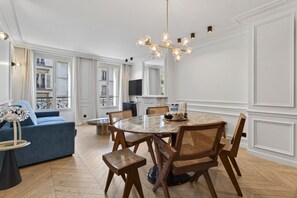 A dining area with a round table, chairs, and a chandelier.