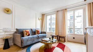 A modern living room with a blue sofa, a round coffee table, and a colorful rug. - #3Bedrooms#Lafayette#Paris10#AC (Paris)