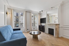 A living room with a blue sofa, a round coffee table, a fireplace, and a television.