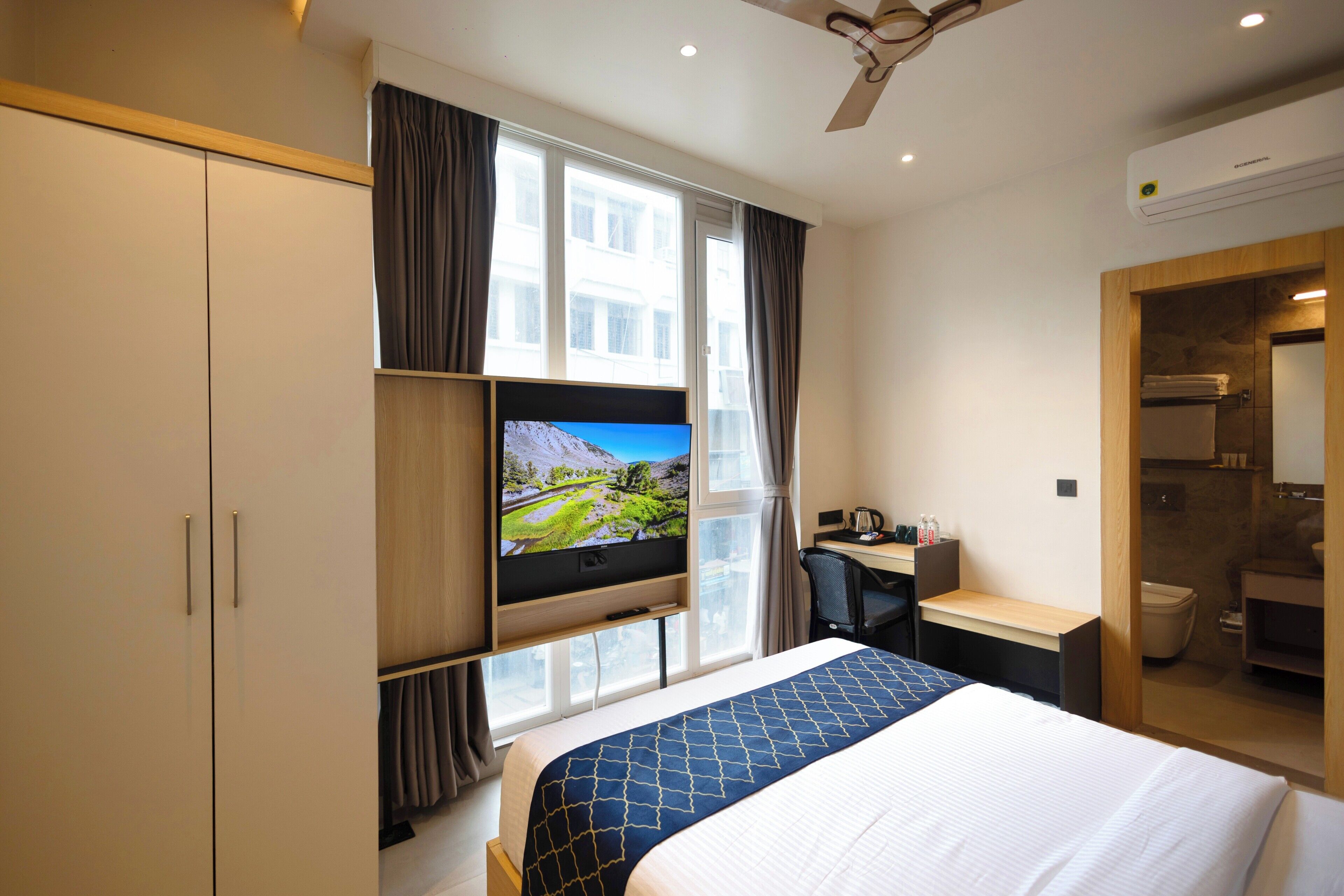 A hotel room with a bed, a desk, a television, and a bathroom.