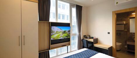 A hotel room with a bed, a desk, a television, and a bathroom.