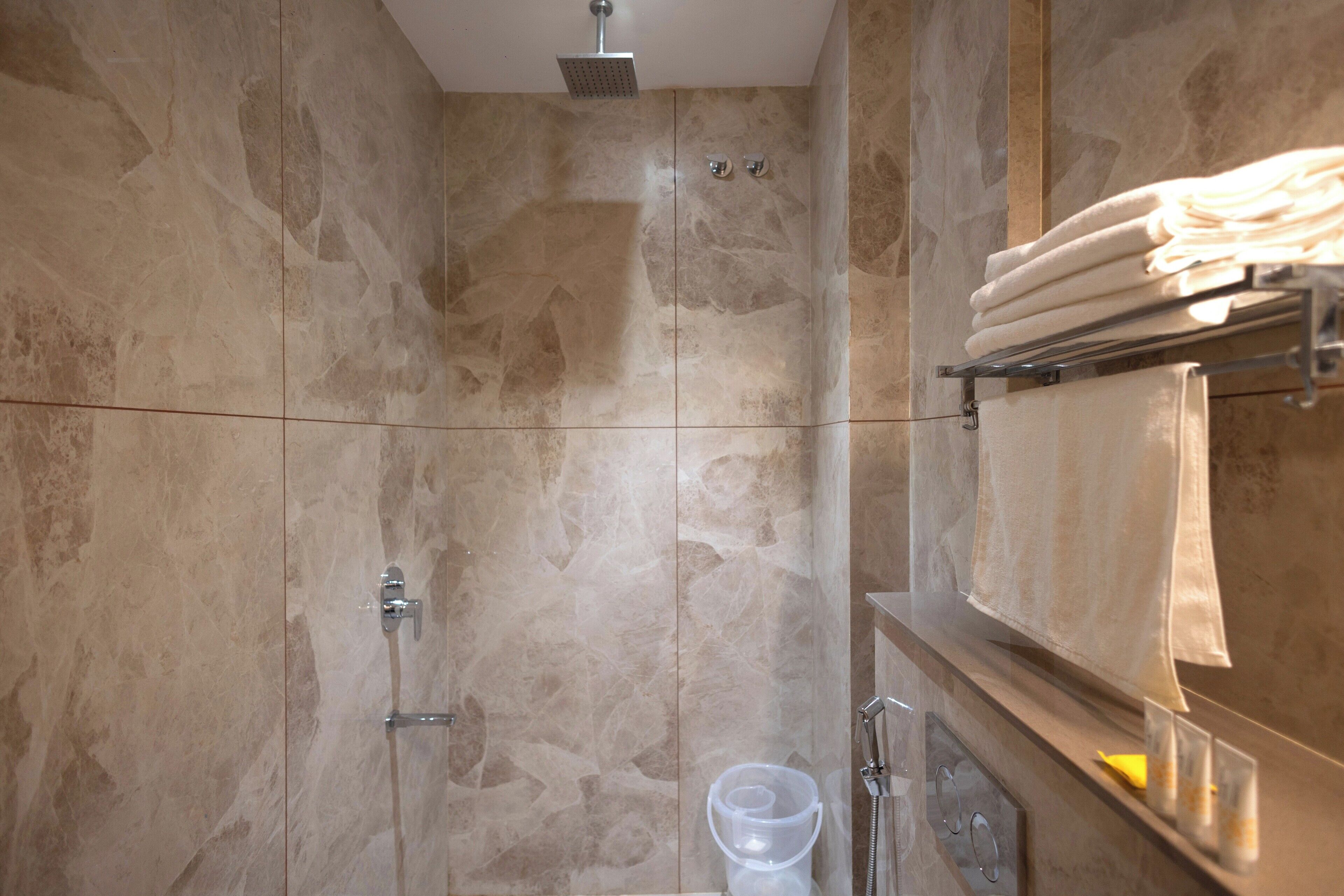 A bathroom with a shower, a towel rack, and a glass of water.