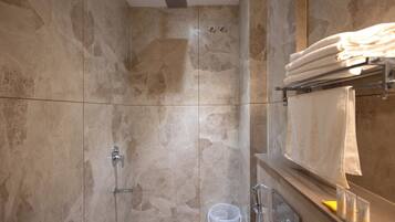A bathroom with a shower, a towel rack, and a glass of water.