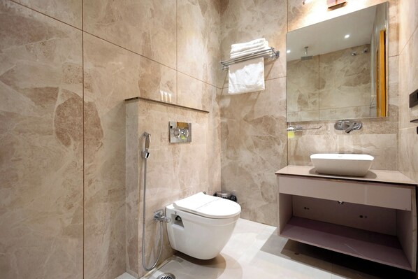 A modern bathroom with a toilet, shower, sink, and a mirror. - Shri Govindam Banaras (Varanasi)