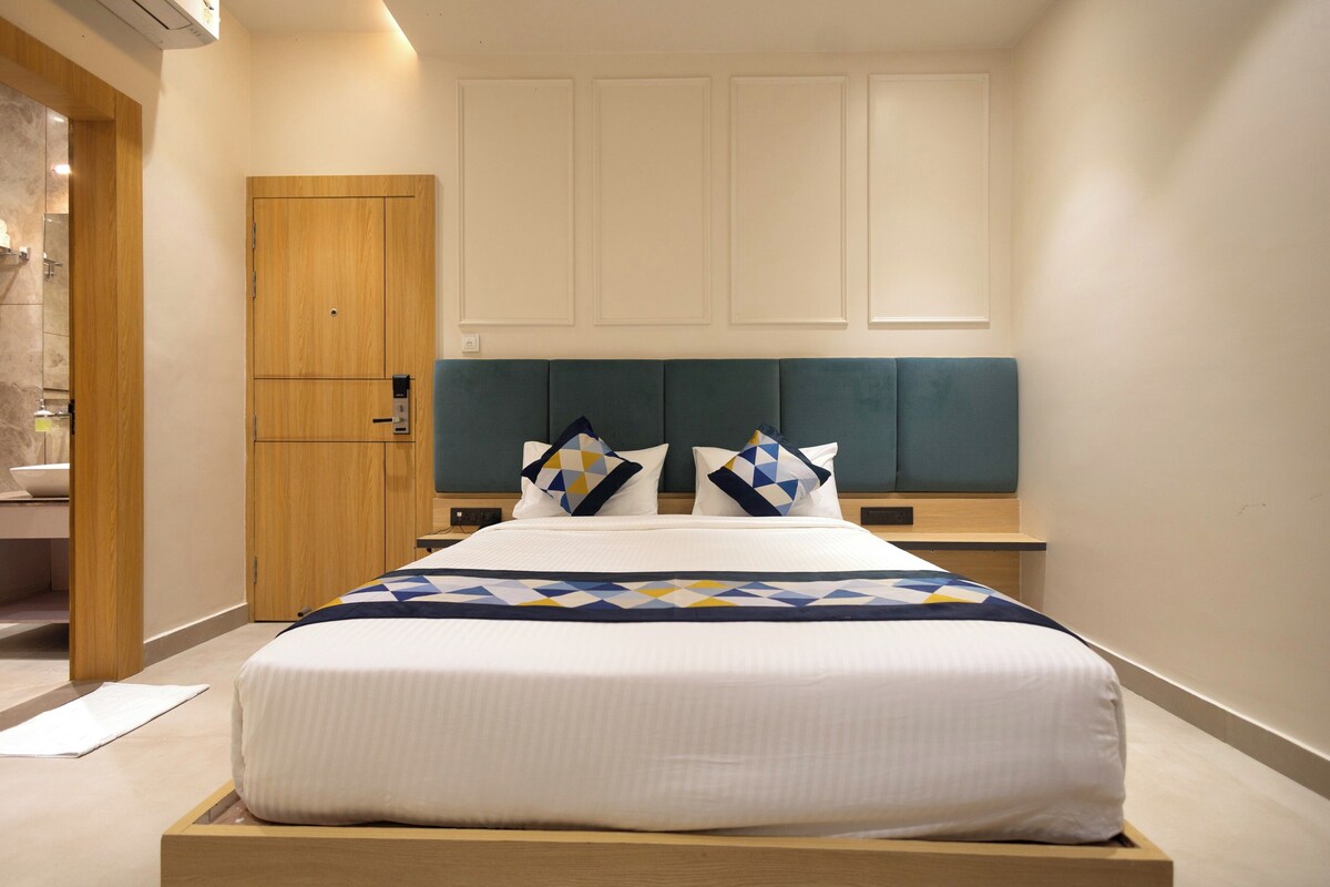 A modern hotel room with a bed, wooden wardrobe, and a headboard.