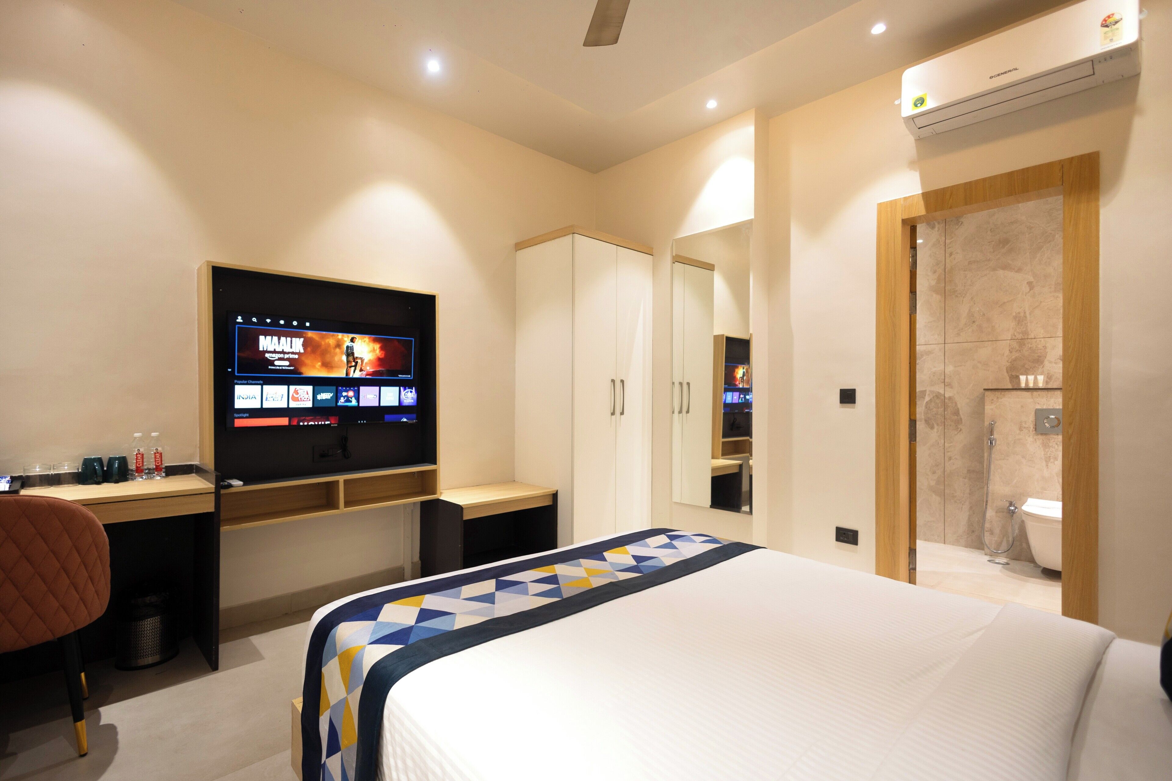 A hotel room with a bed, a desk, a TV, a wardrobe, and a bathroom.