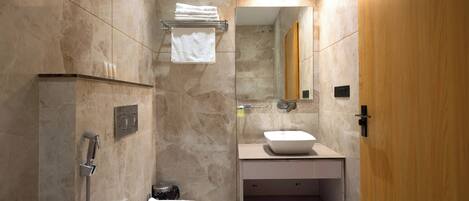 A modern bathroom with a shower, toilet, sink, and mirror.