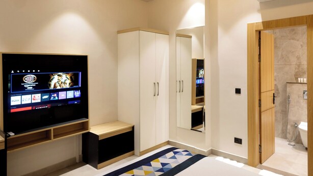 Camera da letto con un letto, una televisione, una ventola a soffitto, un armadio e un bagno.