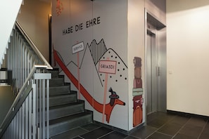 Una escalera con un mural en la pared que muestra un perro, texto y una maleta.