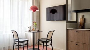 Een moderne kamer met een ronde tafel, twee stoelen, een televisie en een kast.