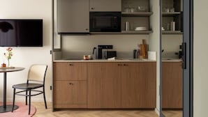 Een moderne keuken met een magnetron, koffiezetapparaat en houten kastjes.