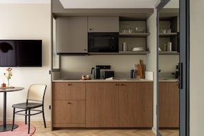 Una cocina moderna con microondas, cafetera y armarios de madera.