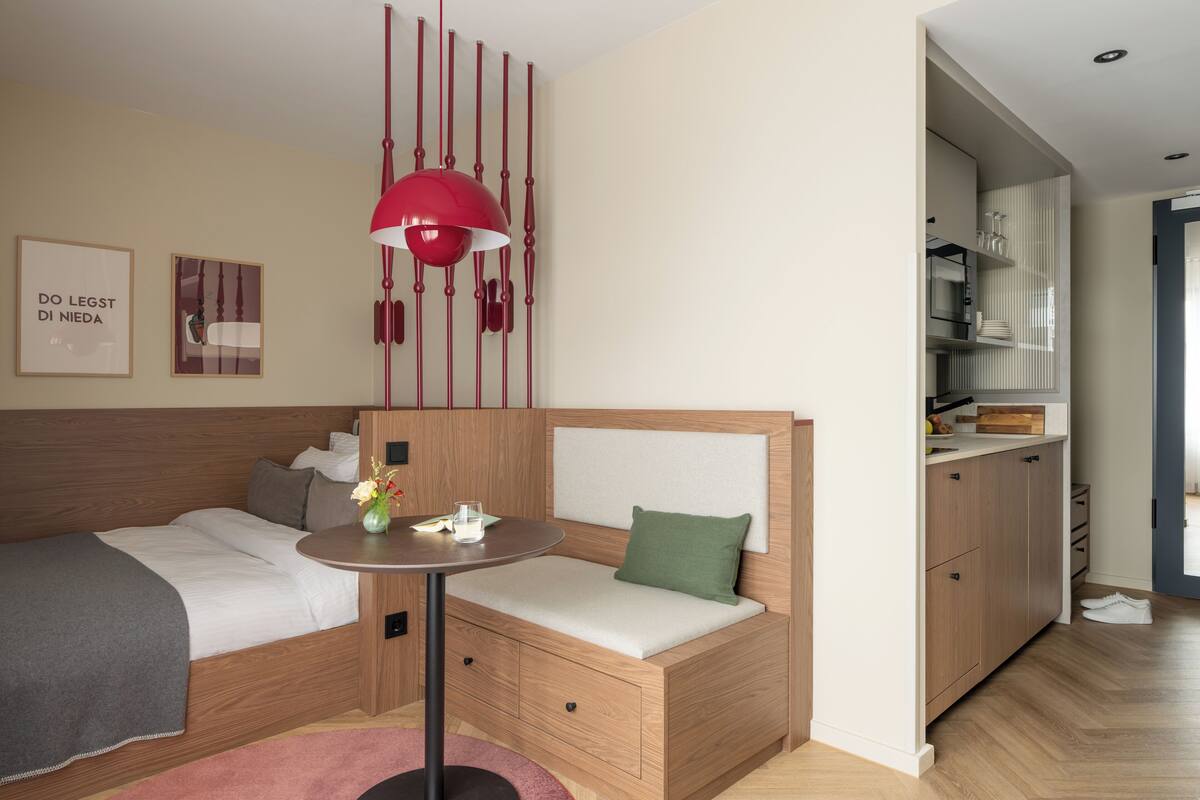 A modern bedroom with a bed, bedside table, and a red pendant light.