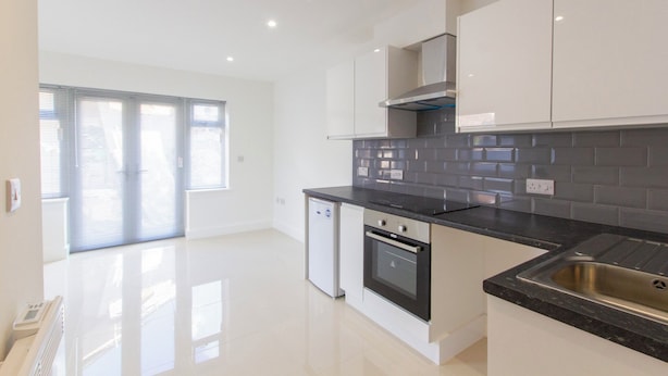 A modern kitchen with a black countertop, stainless steel appliances, and a window with blinds. - Bridge Road - Room 1 (Southampton)