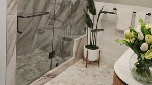 A modern bathroom with a glass-enclosed shower, a white sink, and a vase of flowers. - Tahoe Vista Inn Suite 5 (Tahoe Vista)