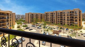A residential building with multiple balconies, a parking area, and a clear blue sky. - 3Beds Apartment in Rehab City (New Cairo)