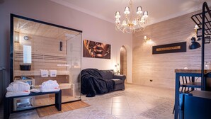 A modern living room with a sofa, a glass partition, a chandelier, and a wooden wall. - Suite del Corso (Ficarazzi)