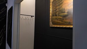 A hallway with a coat rack, a framed painting, and a door. - Suite del Corso (Ficarazzi)