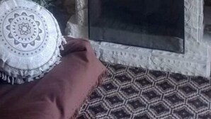 Una chimenea de piedra con un faldón blanco, un plato decorativo y un pequeño estante.