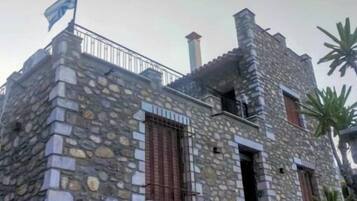 Um edifício de pedra com bandeira, chaminé e varanda.