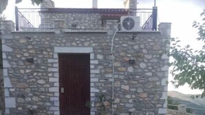 Un edificio de piedra con puerta de madera oscura, plantas en macetas y entrada empavedada.