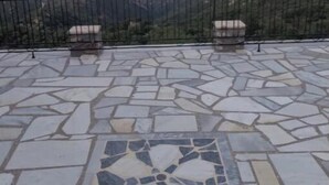 Un patio con suelo de losas de piedra y un mosaico decorativo en el centro, rodeado por una barandilla de metal.
