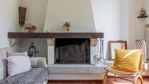 Ein Wohnzimmer mit Kamin, einer Couch, einem Sessel und Dekorationselementen.