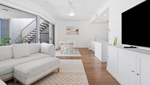 Una sala de estar moderna con sofá, mesa de comedor y zona de cocina.