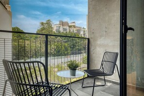 A balcony with two chairs, a small table, and a potted plant.