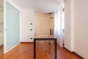 Una habitación con una mesa de vidrio, suelo de madera, un ventanal corredero y una pared blanca.