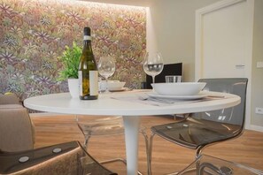 A round dining table with a bottle and two glasses, surrounded by modern chairs. - Truly Verona (Verona)