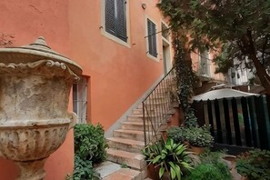 A courtyard with a staircase, a large urn, and potted plants. - Truly Verona (Verona)