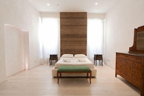 A bedroom with a bed, a dresser, a bench, and a large wooden panel wall. - Truly Verona (Verona)