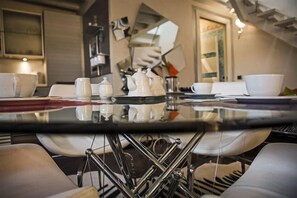 A modern kitchen with a glass-top table, white cups, and a teapot. - Truly Verona (Verona)