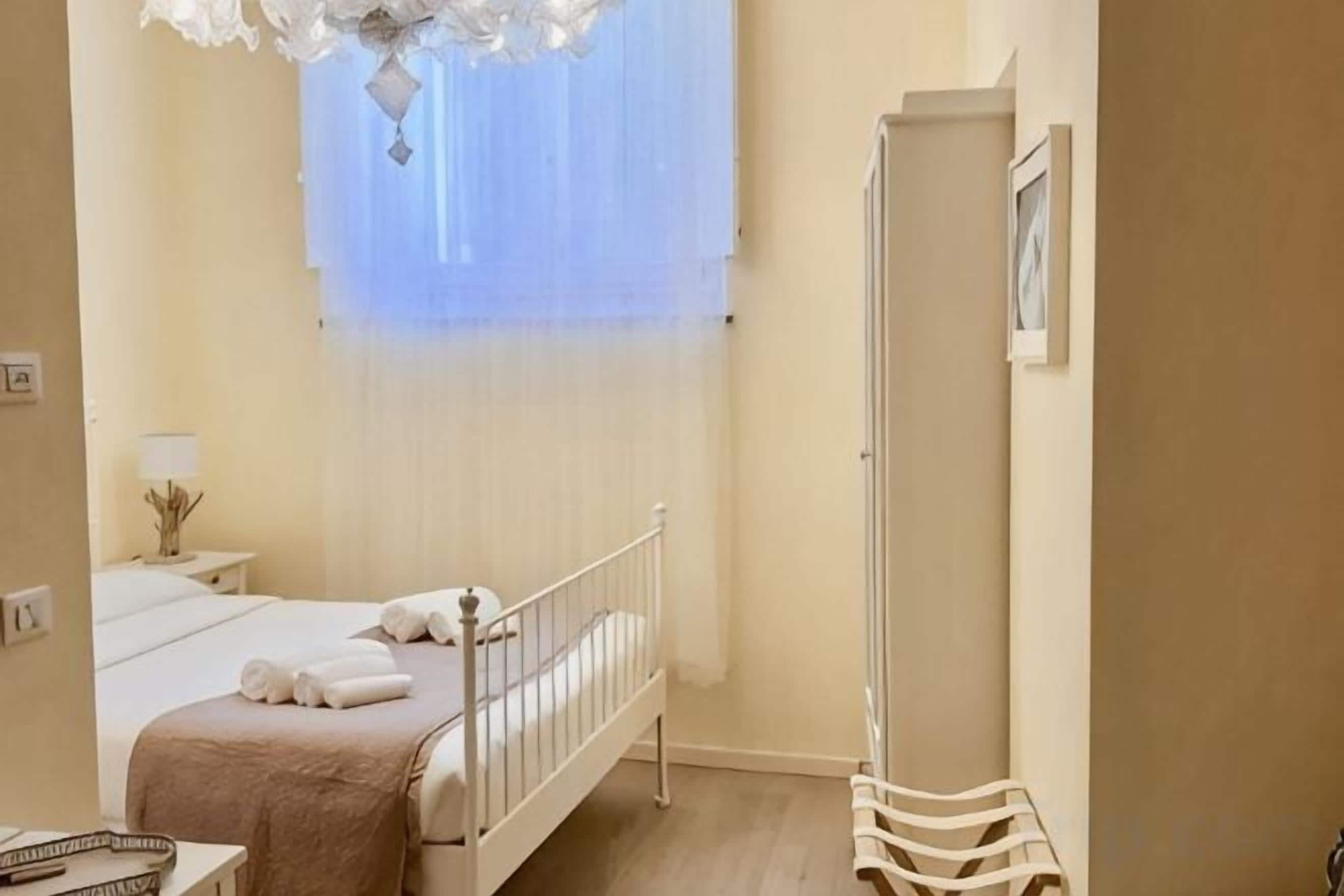 A bedroom with a bed, bedside table, lamp, and a wardrobe.