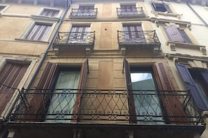 A building facade with multiple windows, some with shutters, and balconies with wrought iron railings. - Truly Verona (Verona)