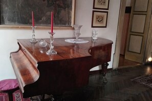 Un piano de madera con tres candelabros y un vaso sobre la mesa.