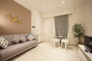 A modern living room with a sofa, a glass table, and a TV. - Truly Verona (Verona)