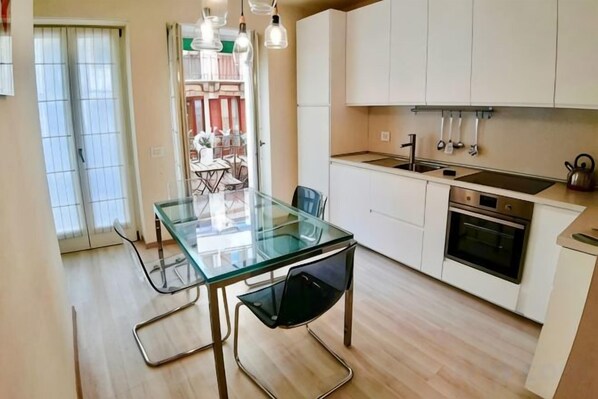 Una cocina moderna con una mesa de comedor de vidrio, armarios blancos y un horno empotrado.
