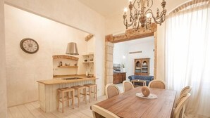 A dining area with a wooden table, chairs, a chandelier, and a view into the kitchen. - Truly Verona (Verona)