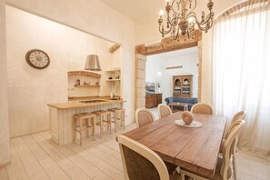 A dining area with a wooden table, chairs, a chandelier, and a view into the kitchen. - Truly Verona (Verona)