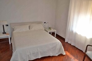 A bedroom with a bed, nightstands, and a window with curtains. - Truly Verona (Verona)