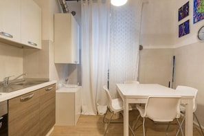 Une cuisine compacte comprenant un évier, un petit plan de travail et un coin repas avec une table et des chaises.