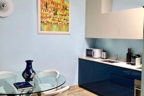 A compact kitchen with a glass table, a microwave, and a sink. - Truly Verona (Verona)
