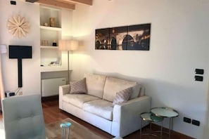 Un salon avec un canapé, une table basse en verre, une lampe et un tableau au mur.