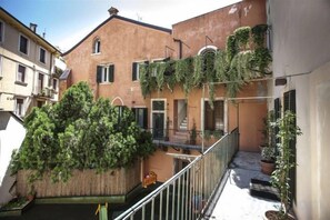 A narrow alleyway with buildings on either side, a wooden fence, and a metal railing. - Truly Verona (Verona)