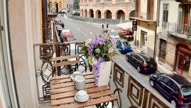 A balcony with a table, chairs, and a vase of flowers. - Truly Verona (Verona)