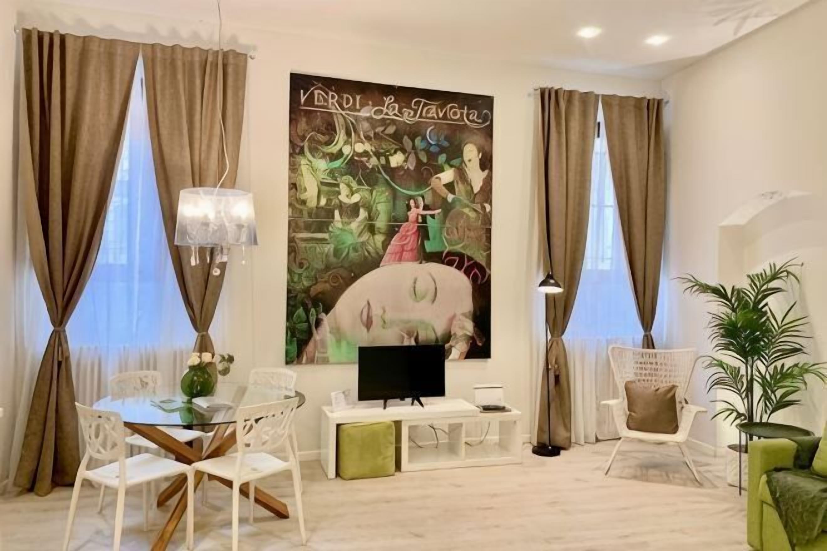 A modern living room with a flat-screen TV, white furniture, a large abstract painting, and a potted plant.